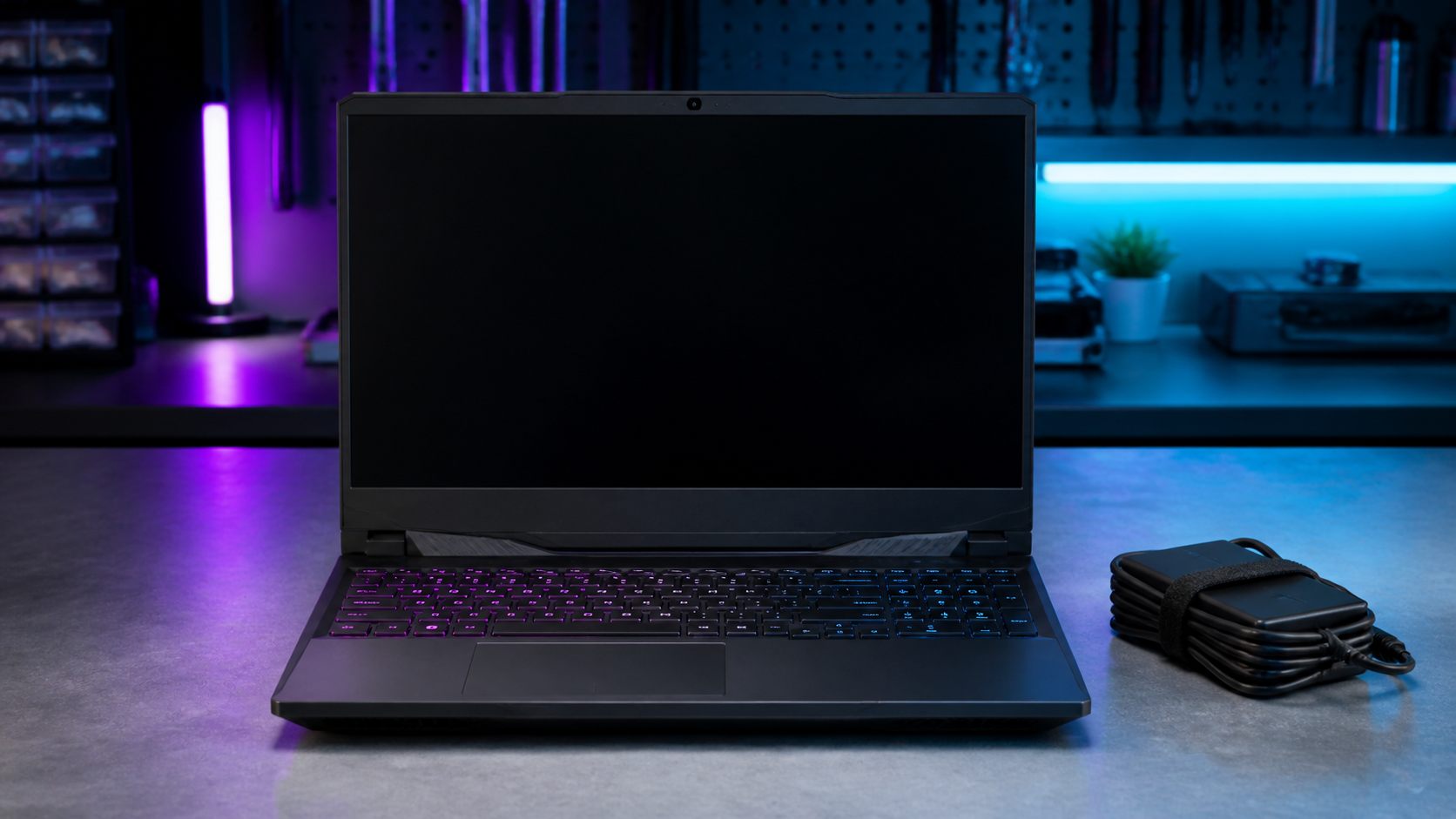 Ausgeschalteter Gaming-Laptop mit Netzteil auf einer Prüfwerkbank
